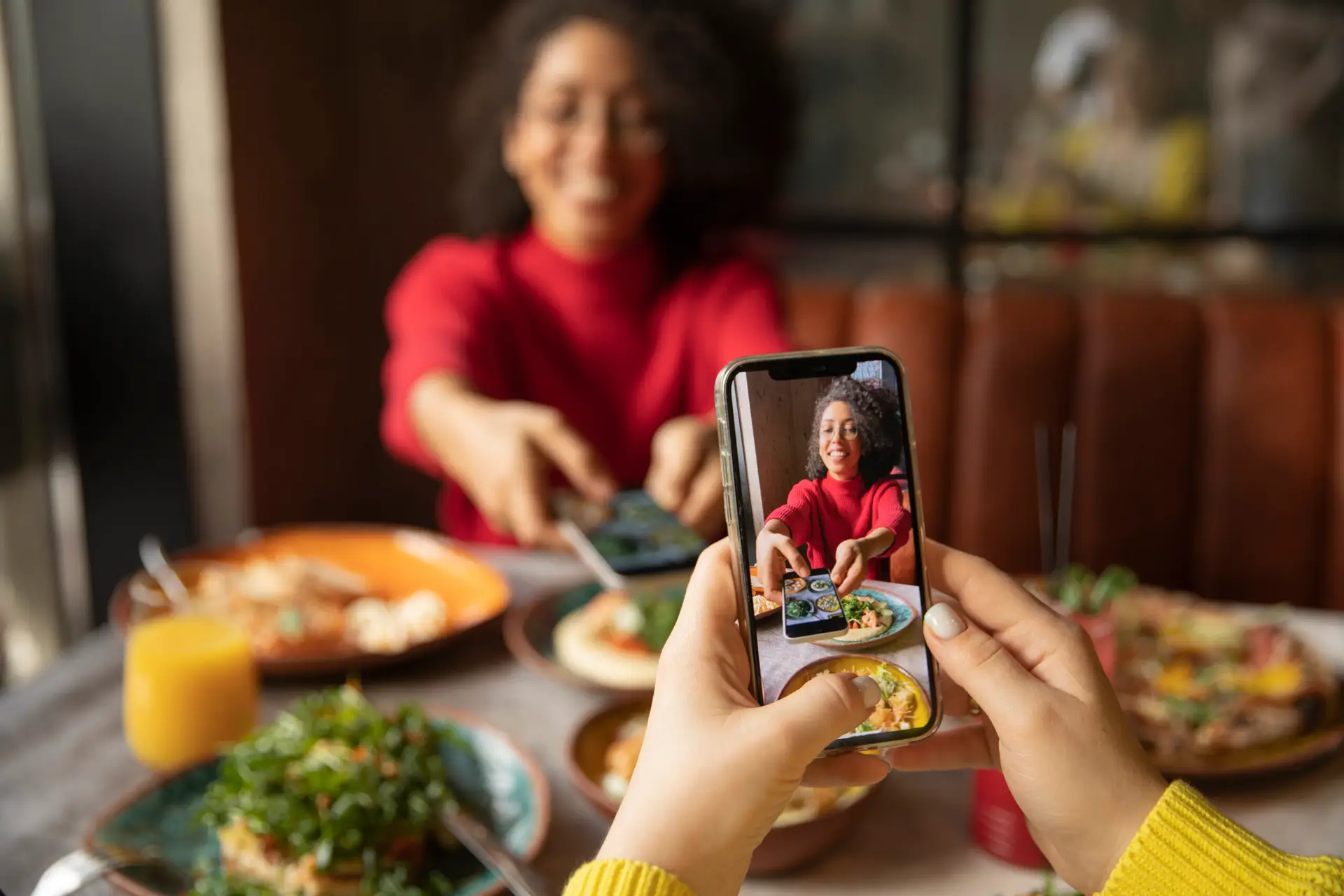 Person in red sweater photographed at restaurant table