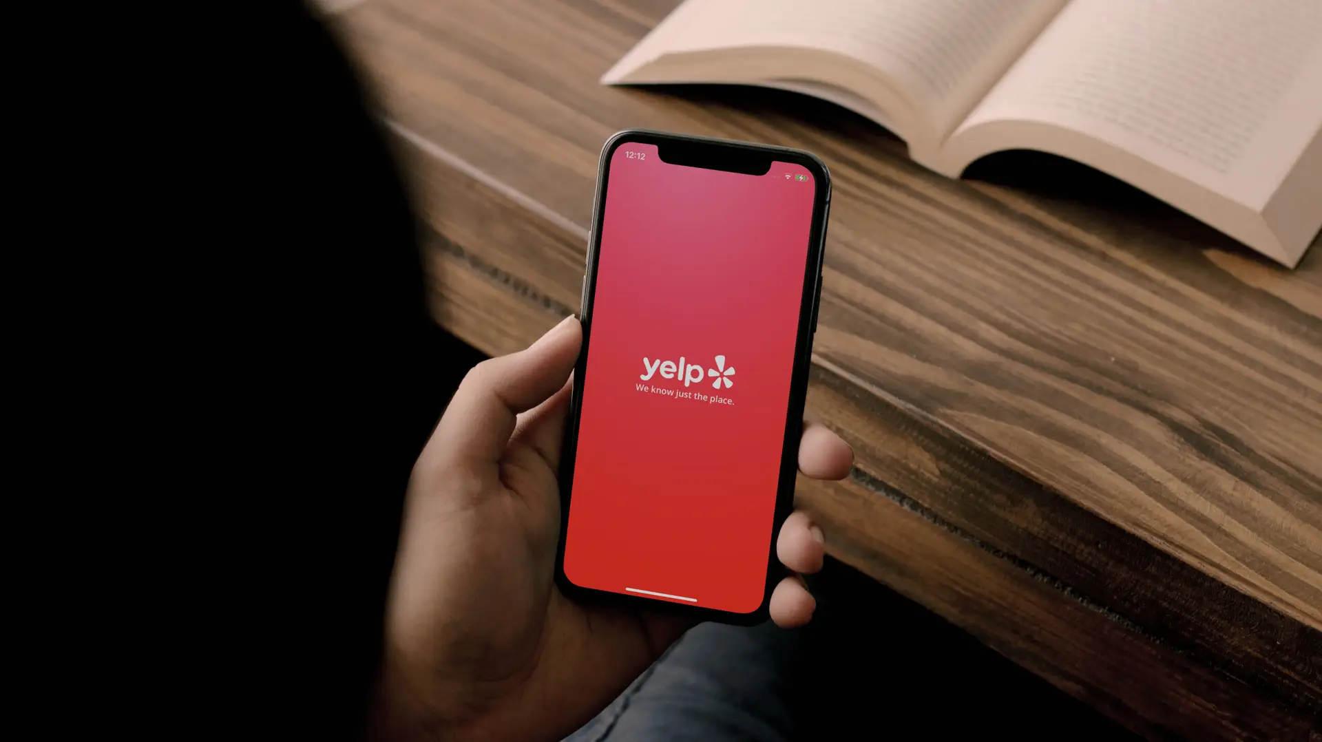 Person holding smartphone with Yelp app open
