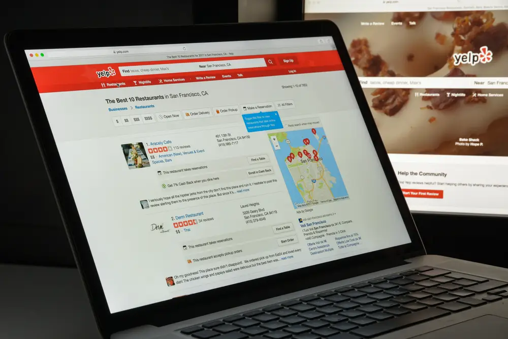 Laptop displaying Yelp restaurant search results.