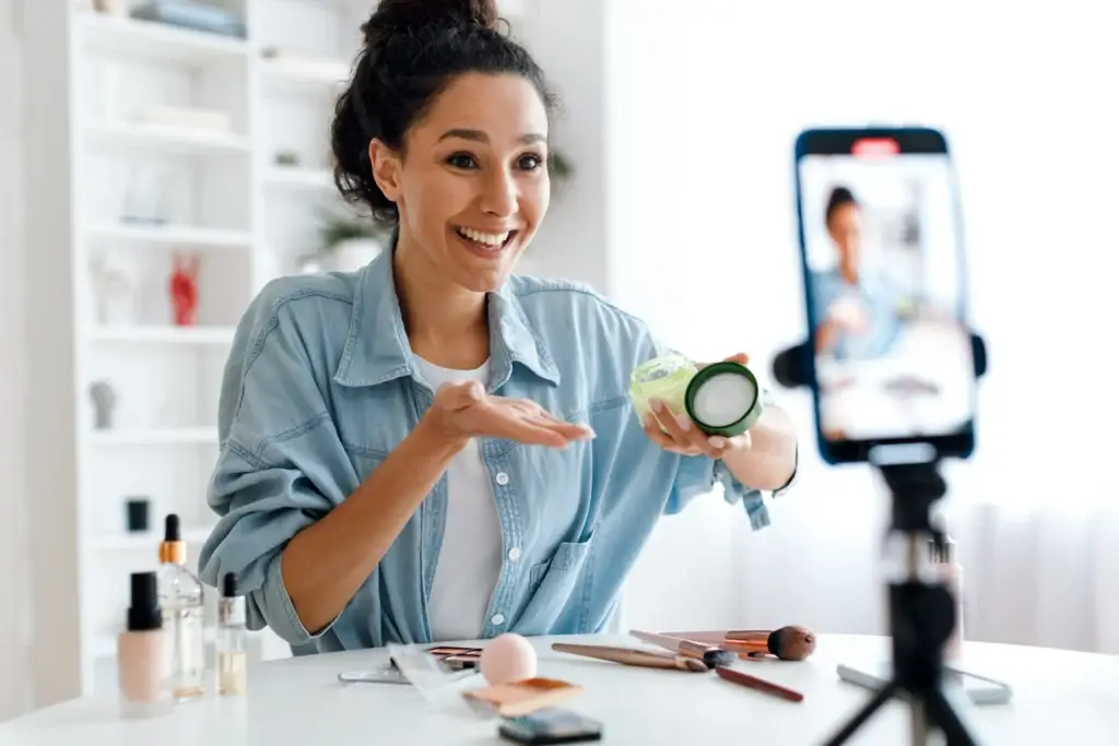 Woman recording beauty tutorial with skincare product.