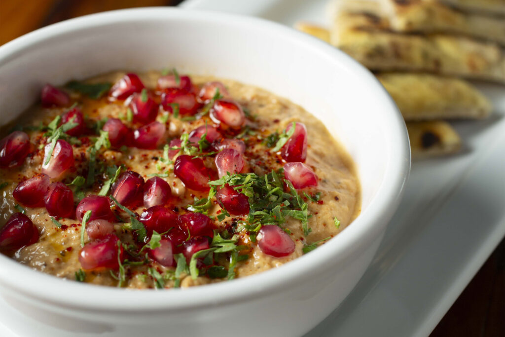 Baba ganoush topped with pomegranate and herbs.