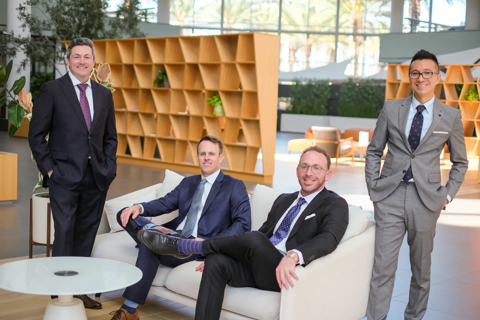 Four professionals in suits in modern office lobby.