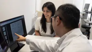 Doctor explaining medical report to patient on computer.