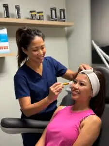 Esthetician applying facial treatment to smiling woman