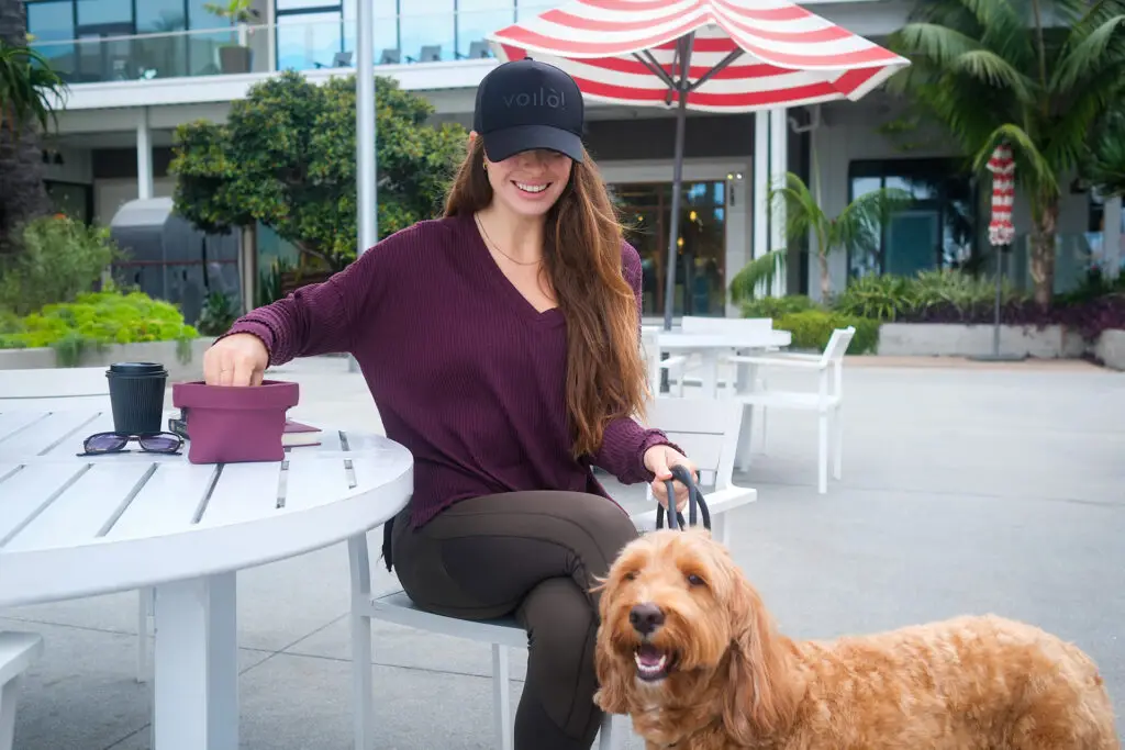 Woman sitting outdoors with her dog and coffee