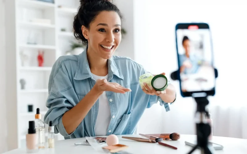 Woman recording beauty tutorial with skincare product.