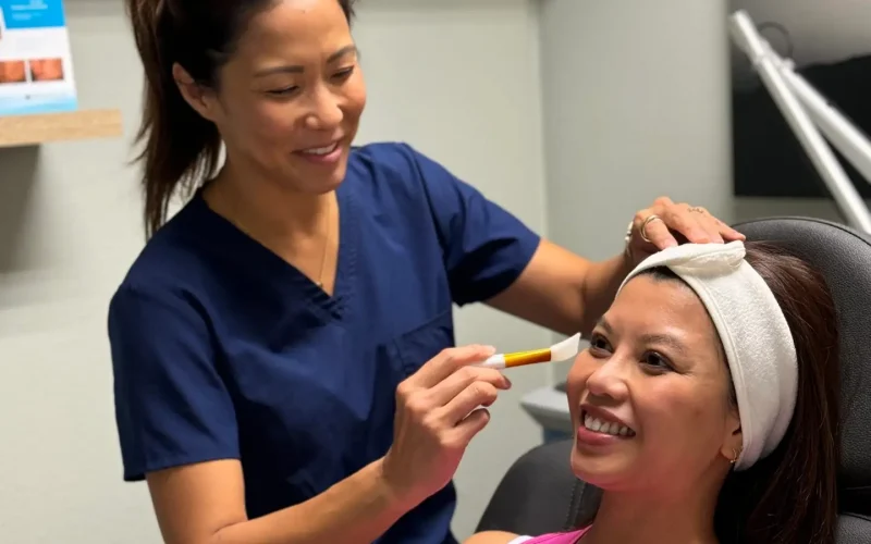 Esthetician applying facial treatment to smiling woman