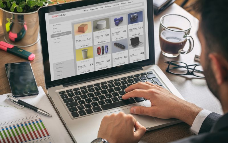 Online shop website developer working with a laptop, office desk background.