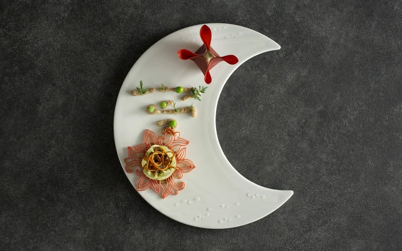 Gourmet dish on crescent moon-shaped plate