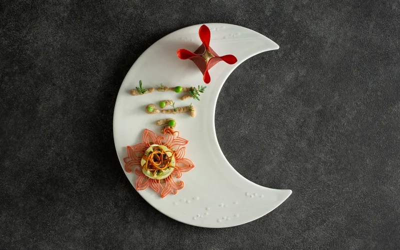 Gourmet dish on crescent moon-shaped plate