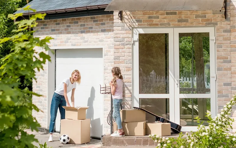 woman unpacking cardboard boxes while daughter standing on stair