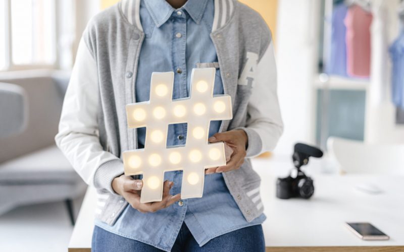 young woman holding hashtag sign in studio
